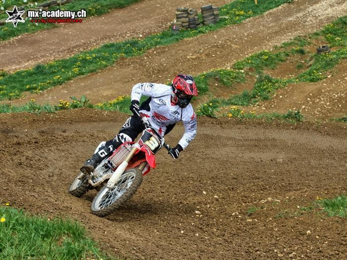 BMX riding with an engine: a motocross rider leaning over, below him a dirt corner on a hillside