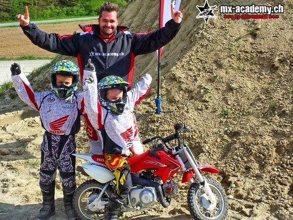 Company outing ideas for families: children in Honda clothing enjoying a small motorcycle, an adult behind them