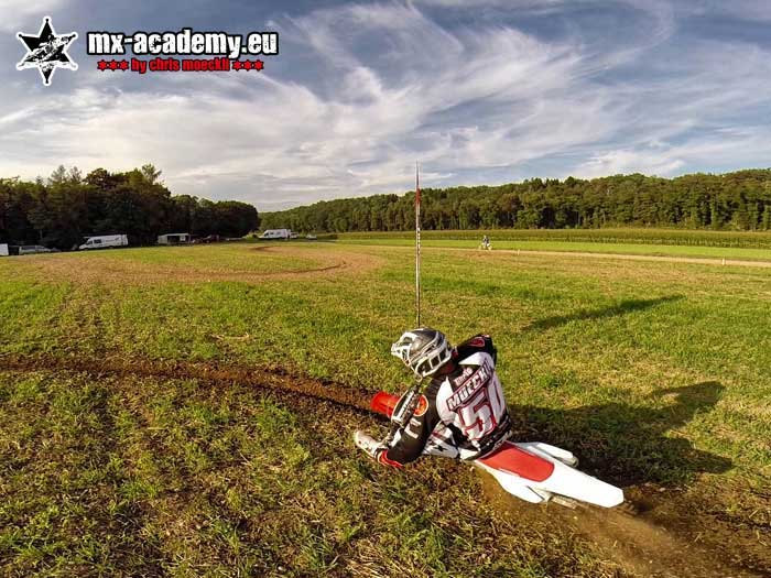 Cornering training on grass: rider at a steep lean angle, the motorcycle tilted far over