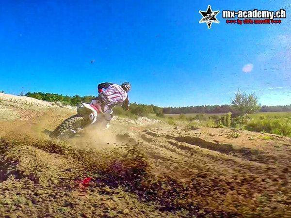 Dirt bike riding: a rider drifts through the corner, clumps of earth fly under a blue sky