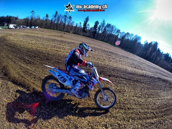 Dirt track riding: a blue motocross bike slides in a drift through a flat corner