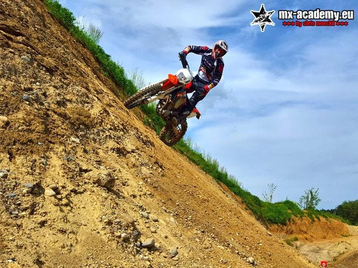 Enduro course on a steep slope: an enduro rider works his way up a steep earth bank