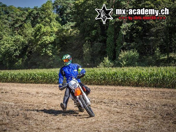 Enduro photos: rider in blue on an orange enduro motorcycle at the edge of a maize field