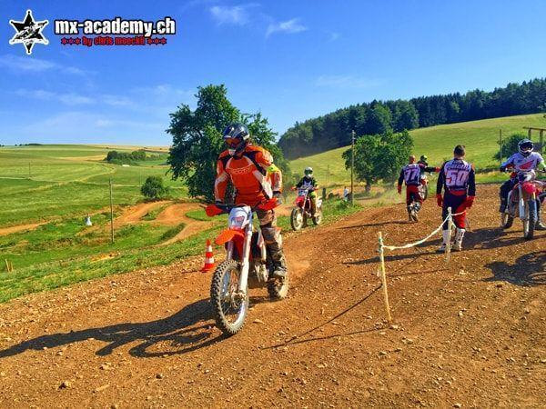 Enduro photos: rider in orange rolls through a lane cordoned off with tape while others wait