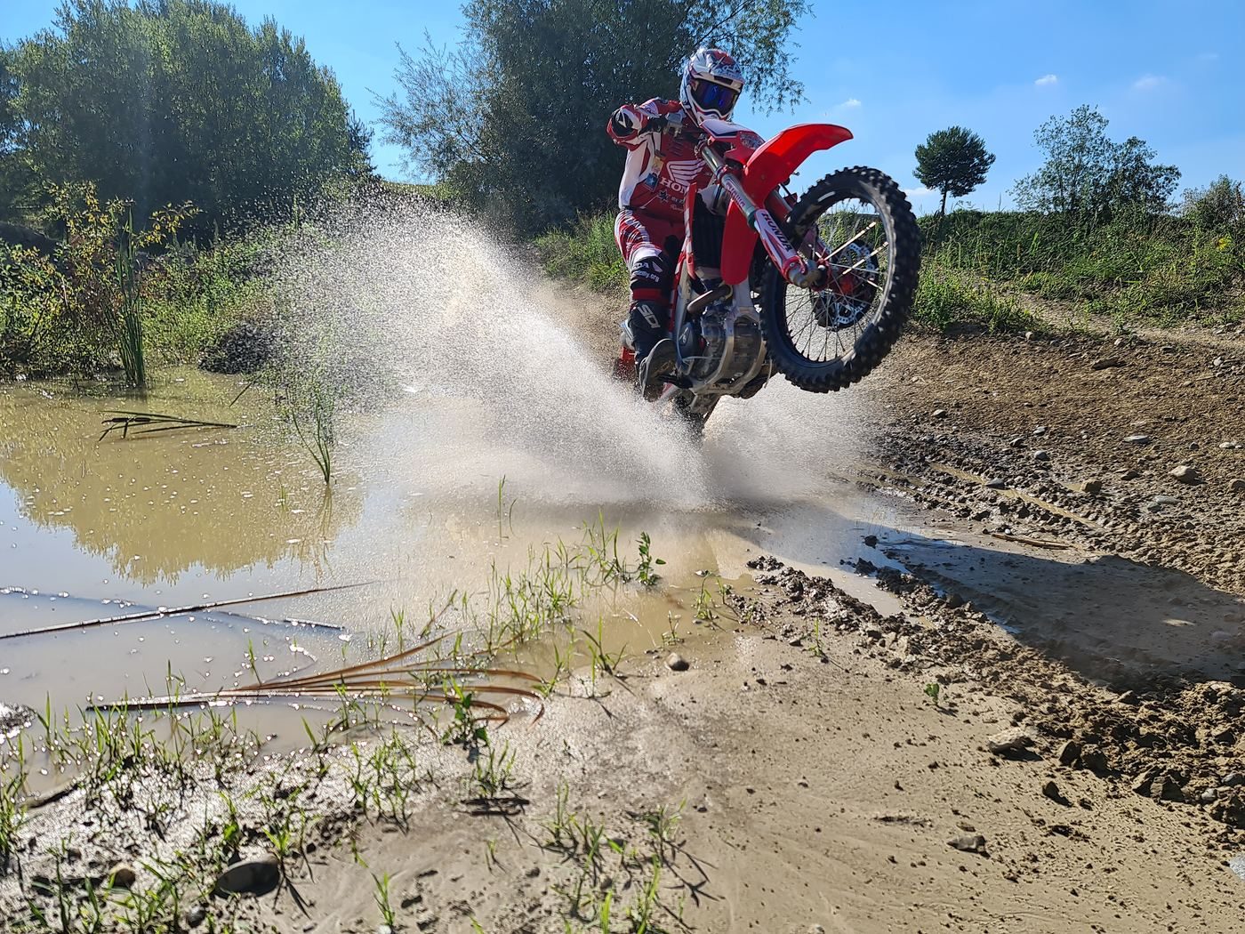 Enduro training: enduro rider crossing a stream with water splashing high