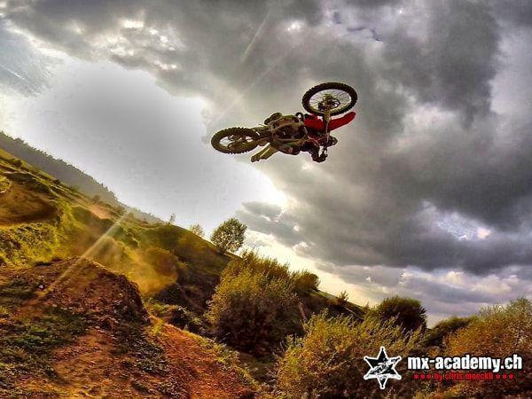 FMX and motocross: a jump with the bike turned sharply sideways, dark clouds in the background