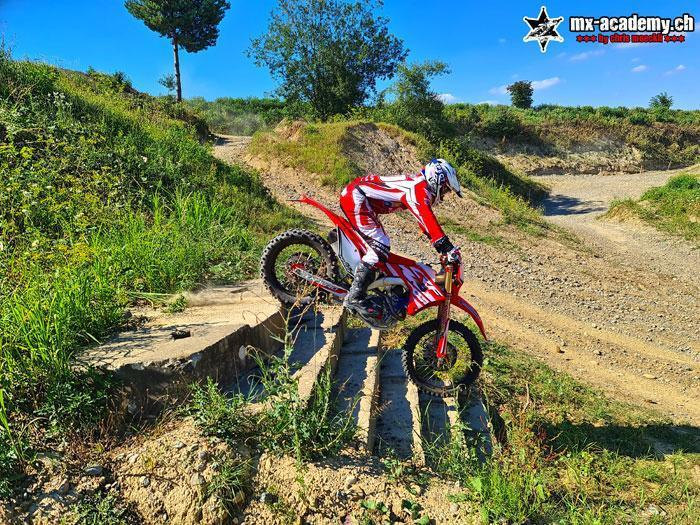 Hard enduro training: a rider steers his enduro up a staircase made of wooden beams