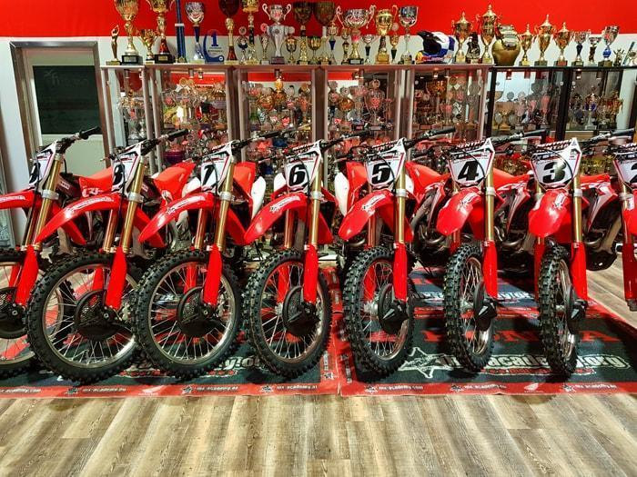 Honda Motoshop: a row of red Honda motocross bikes standing side by side in the shop
