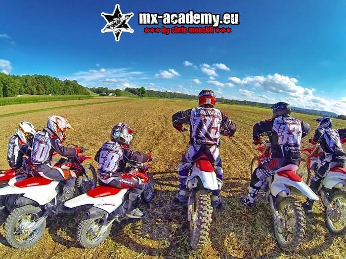 Join a motocross team: a group of riders stands with their motorcycles in the field