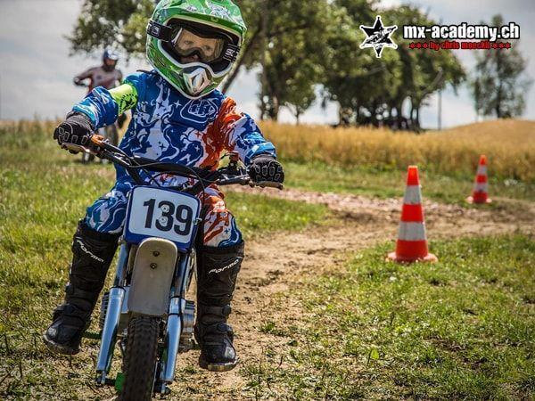 Kids learn to ride a motorcycle: a child with race number 139 on a blue kids' bike, cones for the exercises behind
