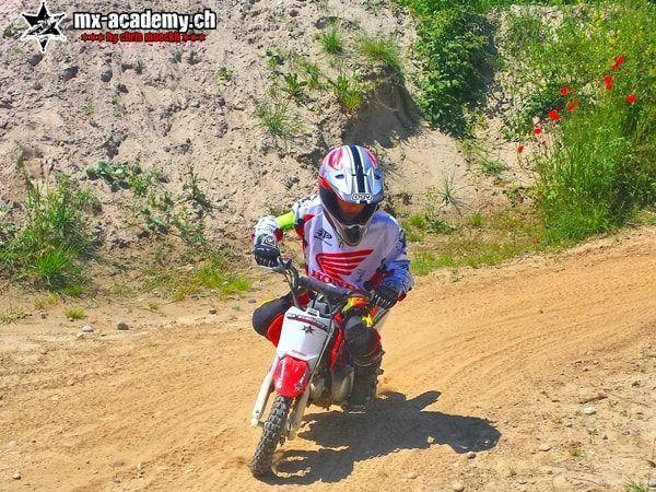 Kids motocross bike in action: a child rides a Honda kids' bike along a sandy path lined with red poppies