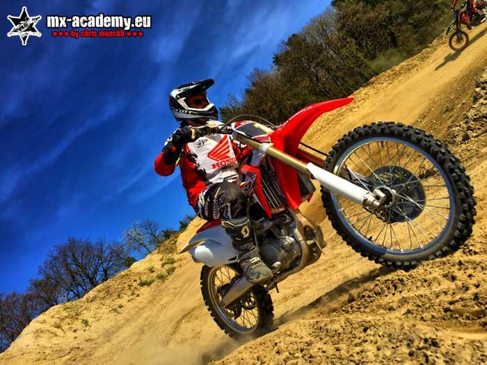 Lean angle practice on a slope: a rider leans his motorcycle well over on a hillside