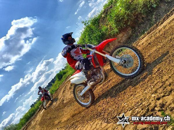 Learn enduro riding on a slope: a rider climbs a steep earth bank with the front wheel lifting