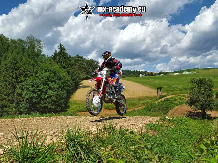 Learn supermoto off-road: a rider takes off with his bike over a crest in the terrain