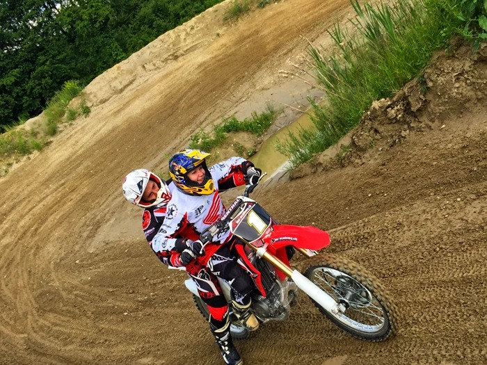 Learning motocross as an adult: coach riding behind a beginner in the corner and showing her the line