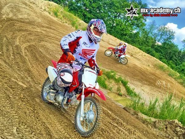 Motocross bikes for kids: a child leans a Honda kids' motorbike into a sandy corner, a second rider follows