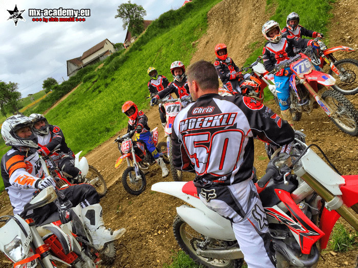 Motocross club members: several riders gather with their coach on a hillside