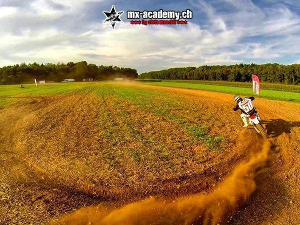 Motocross coach with race number 50 trails a cloud of dust through a corner on the dry dirt track
