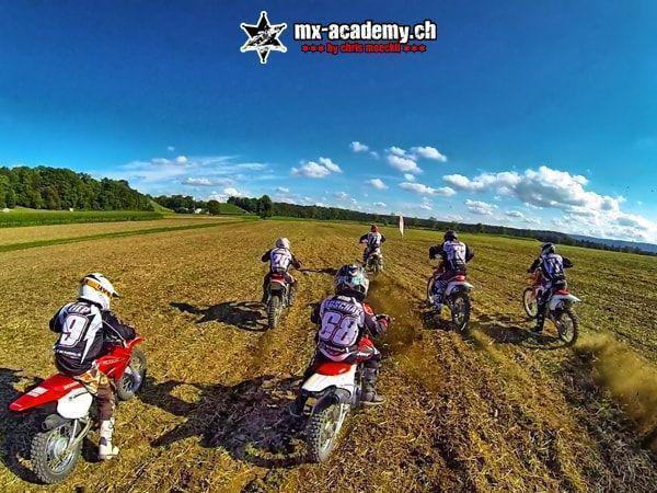 Motocross dates: a group of riders, seen from behind, setting off together across a wide stretch of dirt