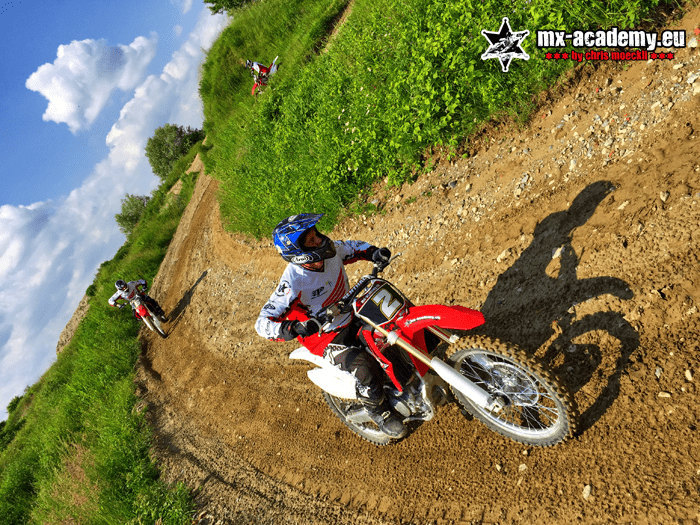 Motocross experience on the bike: rider in the middle of a corner, his shadow falling on the track