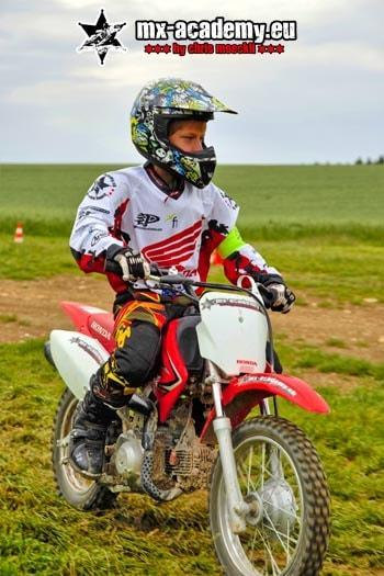 Motocross for teenagers: a young rider with his Honda on a green meadow
