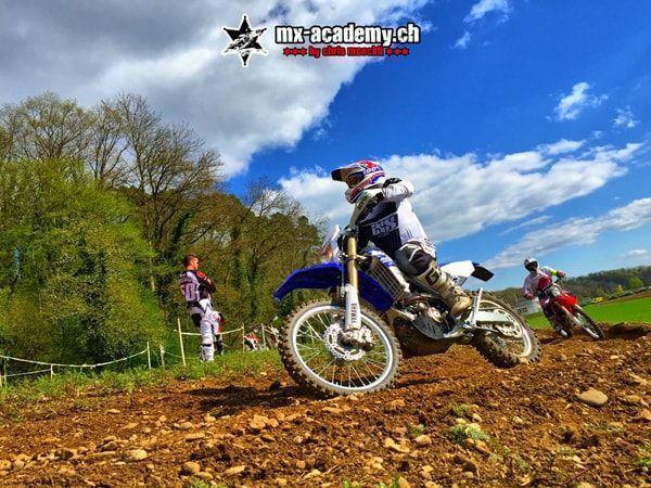 Motocross photos: blue motorcycle leaning in the corner, other riders standing at the trackside