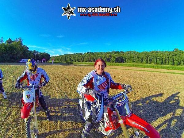 Motocross photos: female and male rider beaming at the camera from their Honda bikes, deep blue sky behind