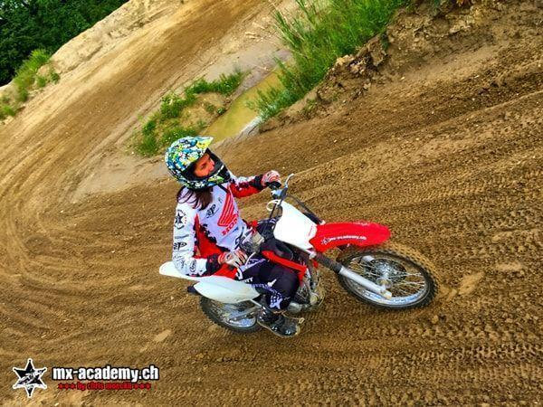 Motocross photos: female rider with a colourful helmet, leaning into a corner on bare earth