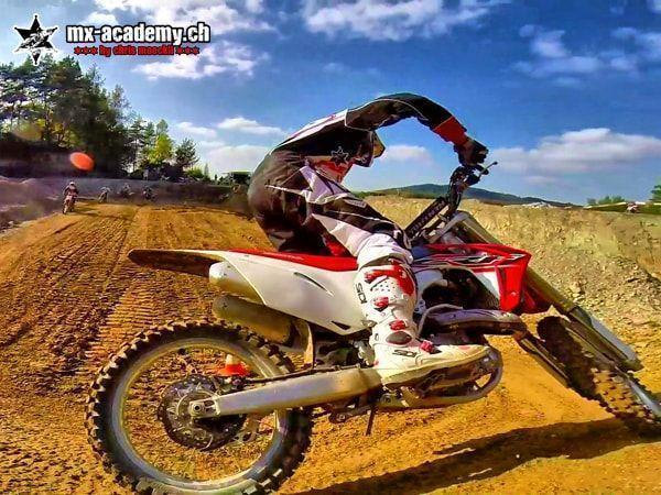 Motocross photos from the rear-wheel camera: rider takes the Honda through the corner standing up