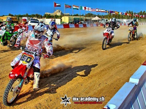 Motocross photos: several riders starting on a sand track in front of flags from many countries