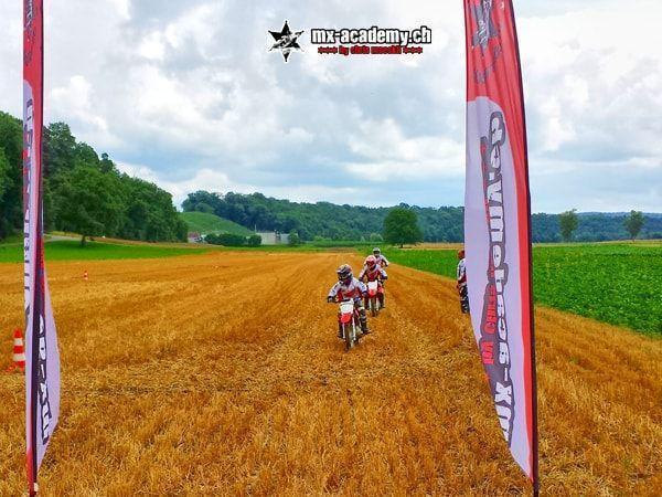 Motocross photos: young riders on kids' motorcycles passing two MX-Academy flags