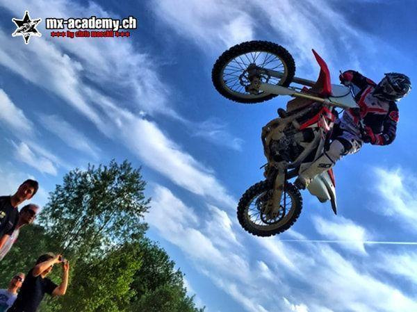 Motocross pictures: a jump seen from a worm's-eye view, spectators at the left edge