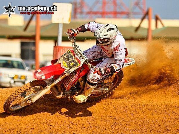 Motocross pictures: number 150 in the corner, dirt flying, buildings in the background