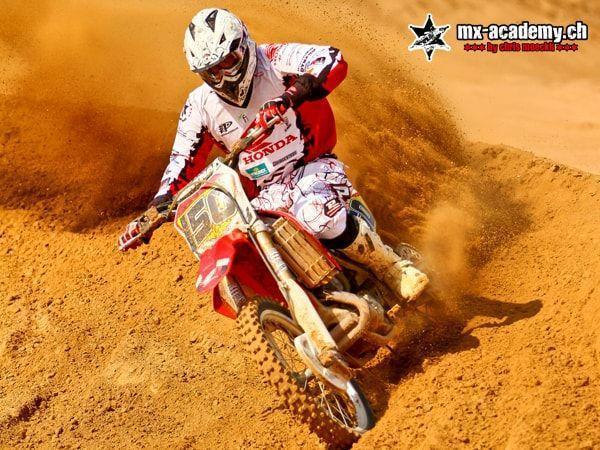 Motocross pictures: rider with race number 150 in the sand corner, sand spraying out to the side