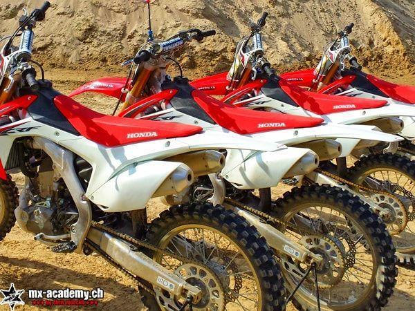 Motocross pictures: several Honda CRF bikes side by side in front of a sand mound, close-up