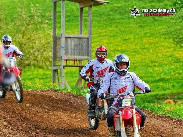 Motocross pictures: three riders in Honda jerseys riding one behind the other, a hunting stand at the back