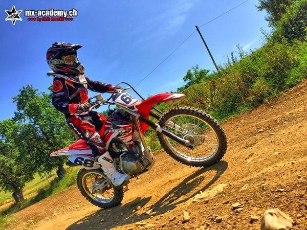 Motocross pictures: young rider with race number 68 lifting the front wheel of his Honda on a slope