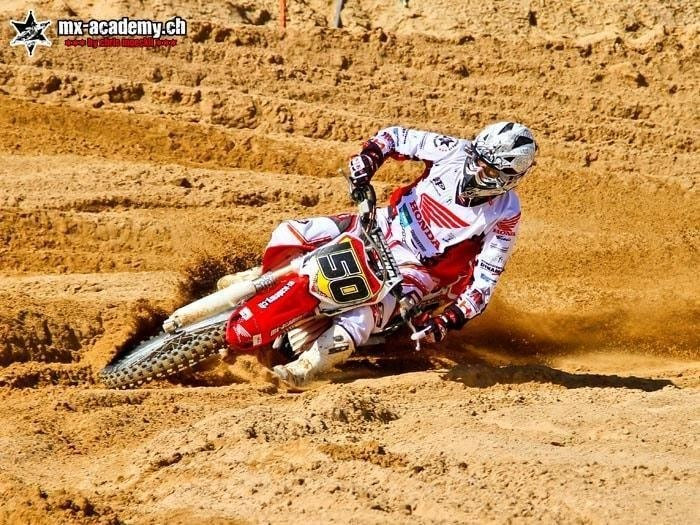 Motocross training: rider with start number 50 leaning into the sand corner