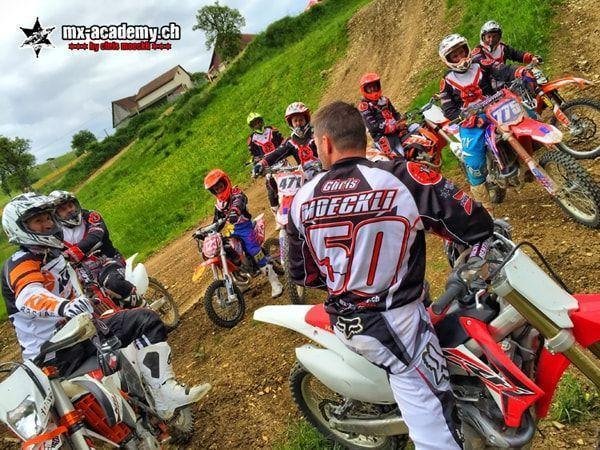 Motocross videos with kids on a slope: rider with race number 50 chats with children and teenagers