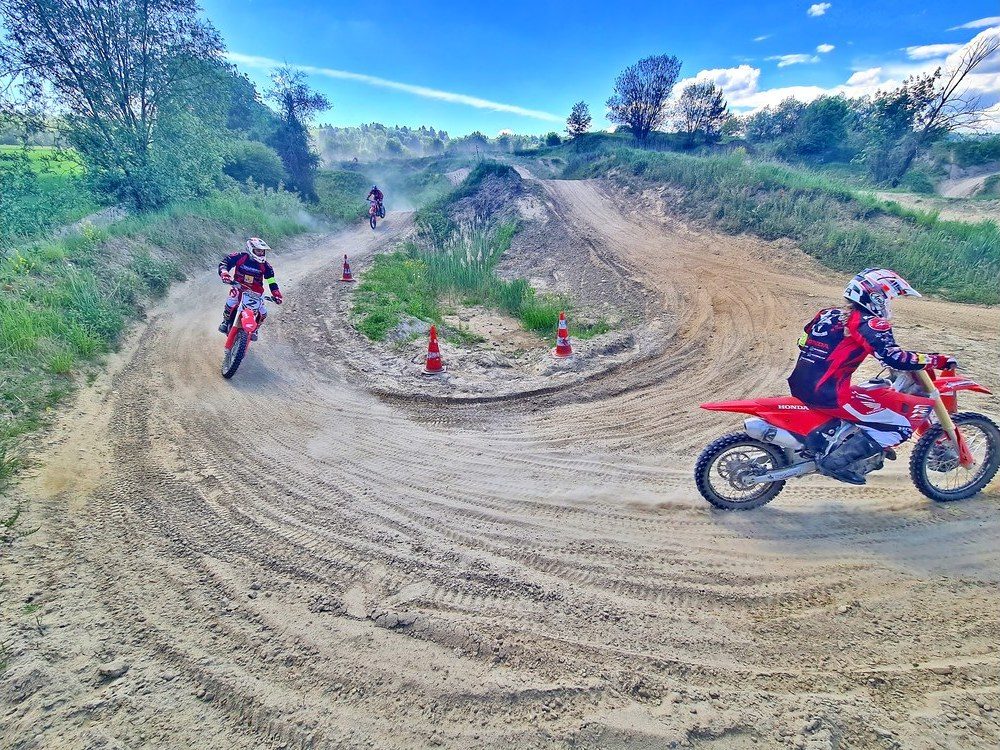Motorcycle training: a newcomer on a red Honda on the practice track, with cones to the left and right of the lane