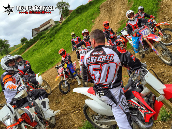 MX-Academy team: motocross coach with race number 50 explains the next exercise to a group of riders