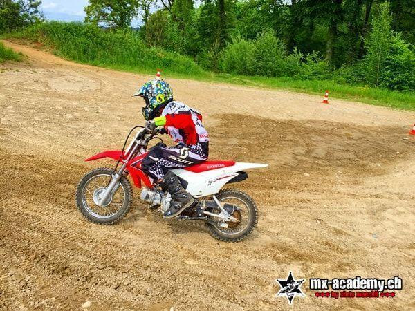 MX photos: child on a red Honda riding through a corner on a sandy area with cones
