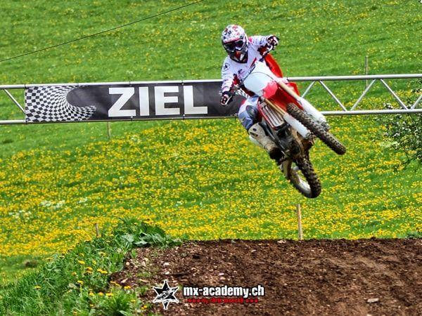 MX photos: rider jumps over the dandelion meadow, a finish banner behind him