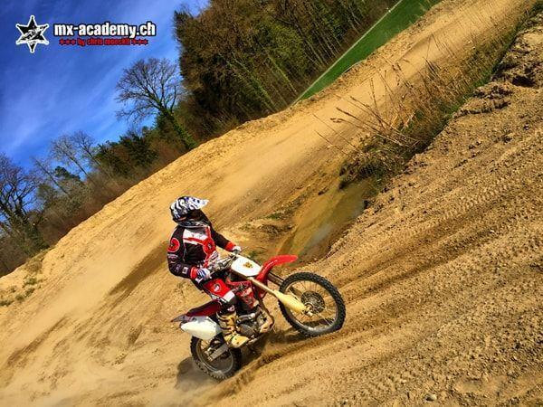 MX photos: sand corner photographed at an angle, a young rider steering his Honda through it