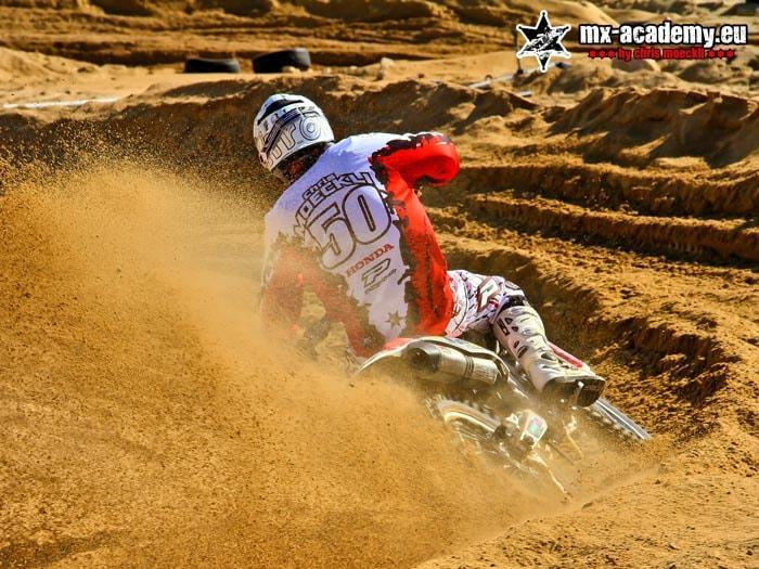 MX training in the sand: a rider with race number 50 rides through a deep sand corner