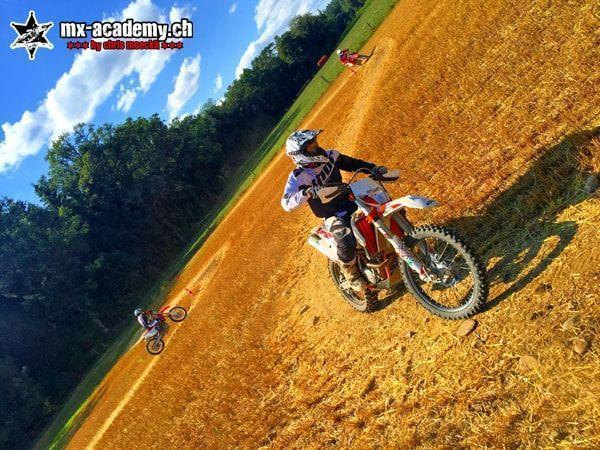 Off-road motorcycle in action: rider on an orange bike in dry terrain, with a tilted horizon