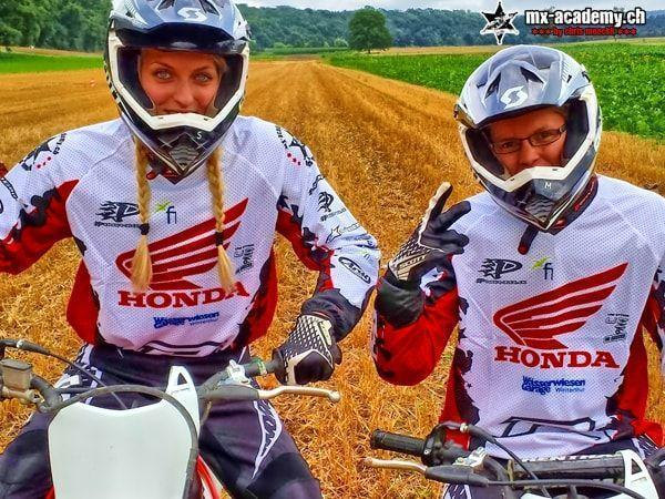 Off-road motorcycle riding: two riders in Honda jerseys, the woman wearing braids, the man wearing goggles