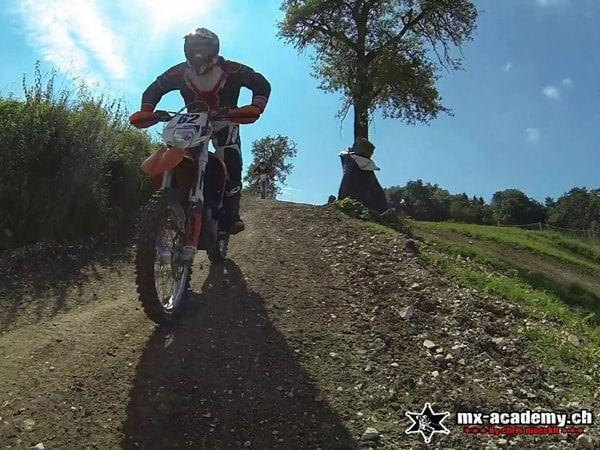 Off-road riding: an orange motorcycle rolls along the dirt track head-on towards the camera