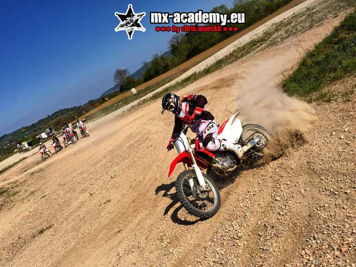 Supermoto off-road training: a rider pulls a cloud of dust behind him on loose ground