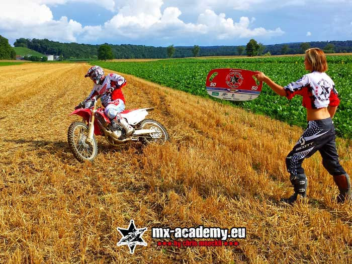 Supermoto training off-road: a helper raises the flag and the female rider sets off
